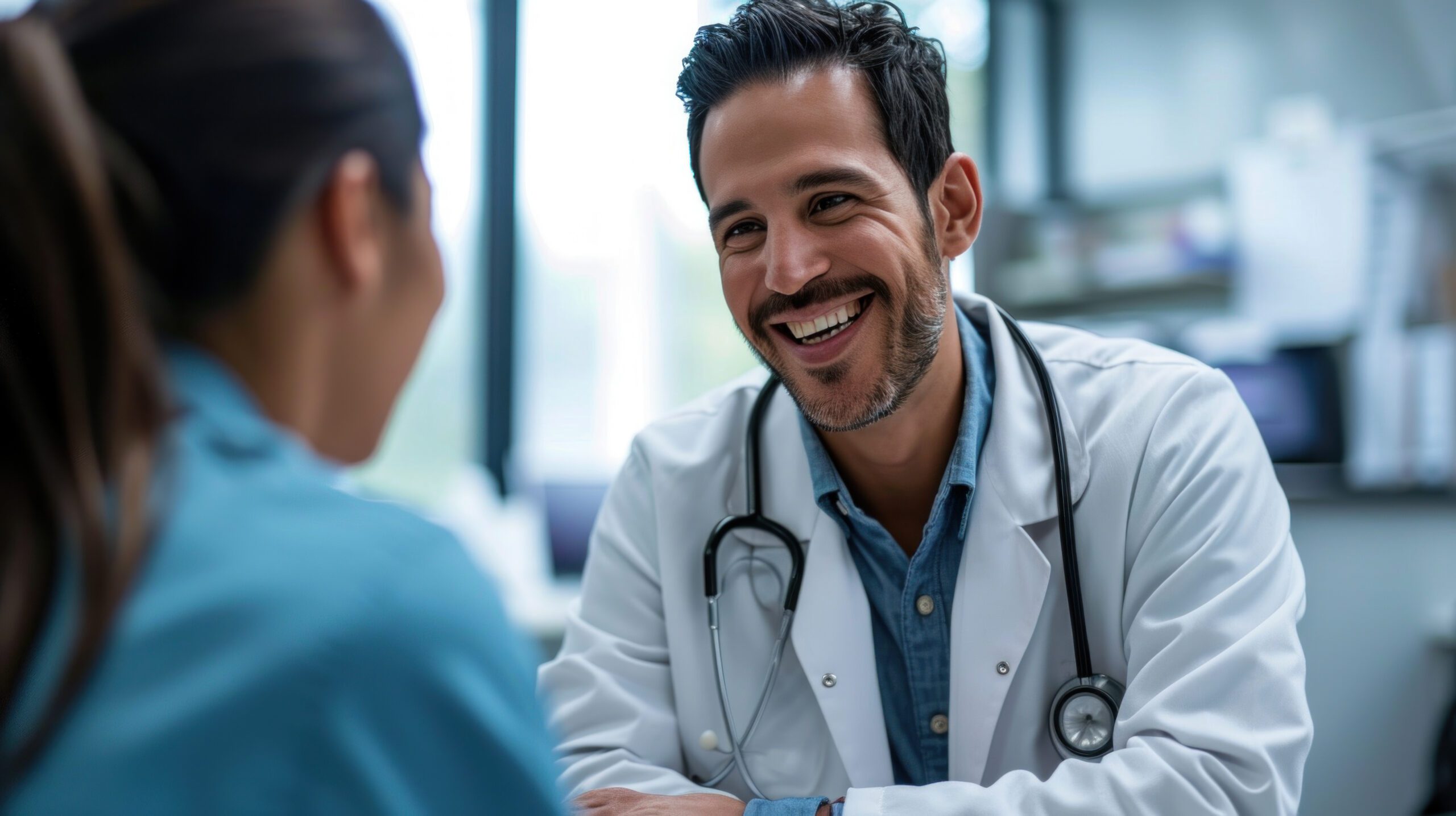 A smiling mid adult male doctor listens as a female patient discusses her health