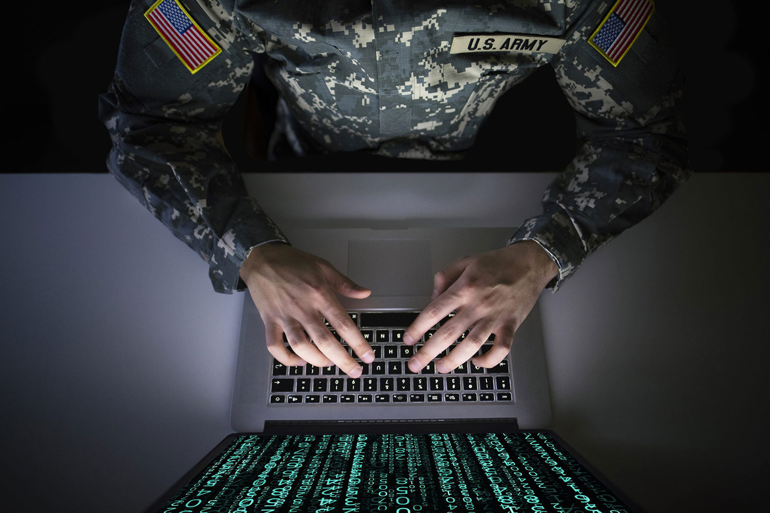 American soldier in military uniform typing on a laptop, demonstrating By Light's ability to provide AI-driven support.